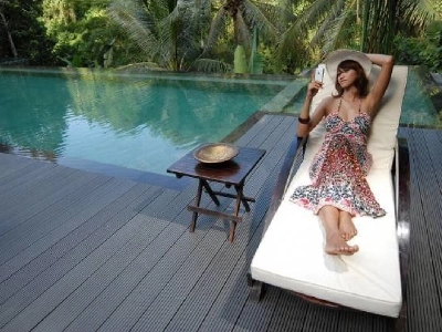 Mujer descansando en reposera sobre piso deck WPC antideslizante y cómodo al tacto en borde de piscina